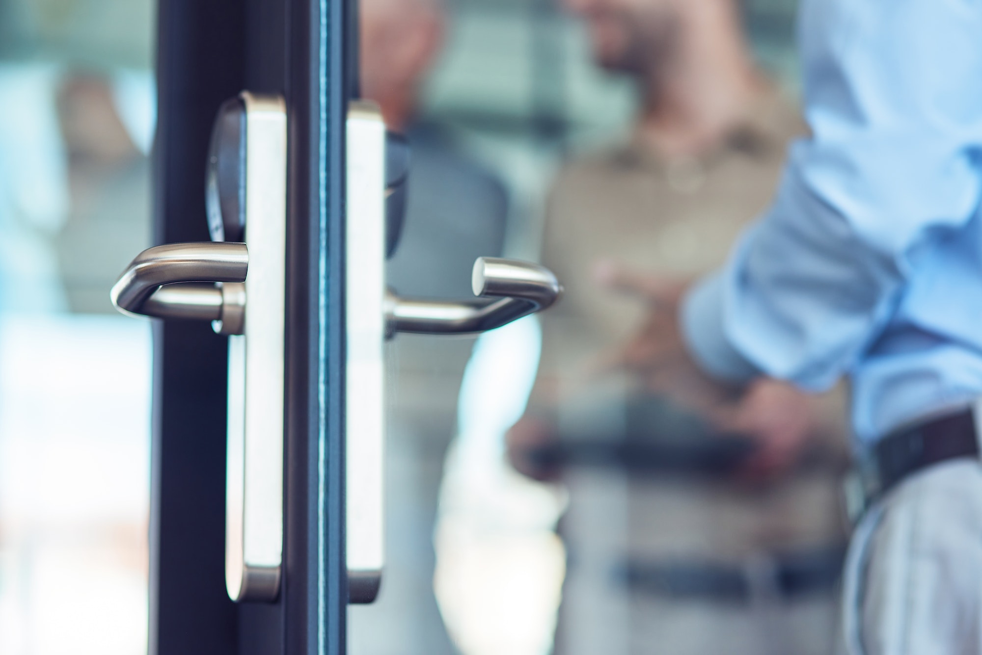 Businessman entering at work, opening glass door in the modern office, selective focus