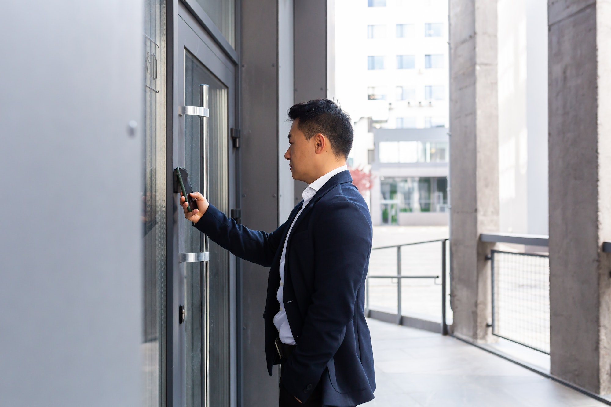 Successful Asian businessman opens the door of the office center using a smartphone